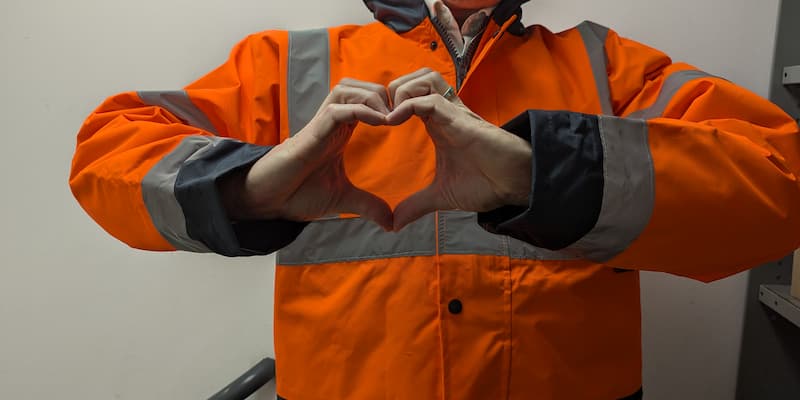 Construction worker wearing hi-vis making a heart sign with hands